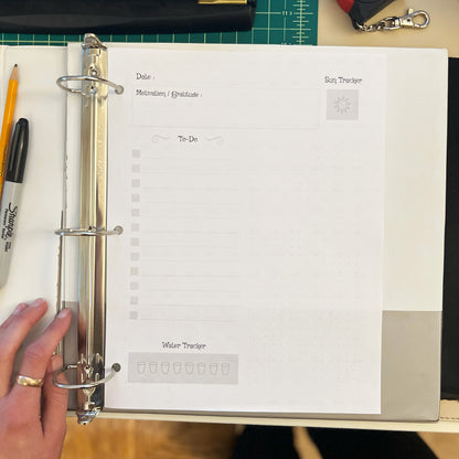 Open planner with a hand holding it on a desk with office supplies.