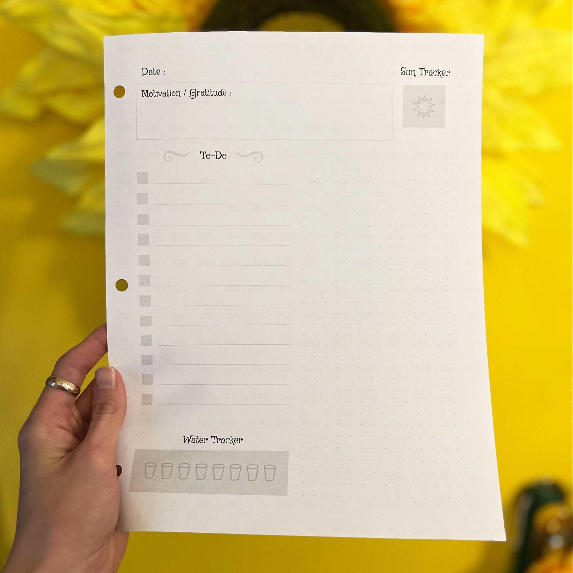 Hand holding a planner sheet with sunflower in the background